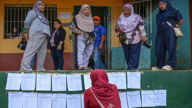 A voter looks for her precinct number posted on a wall of a school building in Saguiaran on the southern island of Mindanao on September 14, 2026. Voters across the Philippines' autonomous Muslim region began casting ballots for their first elected p