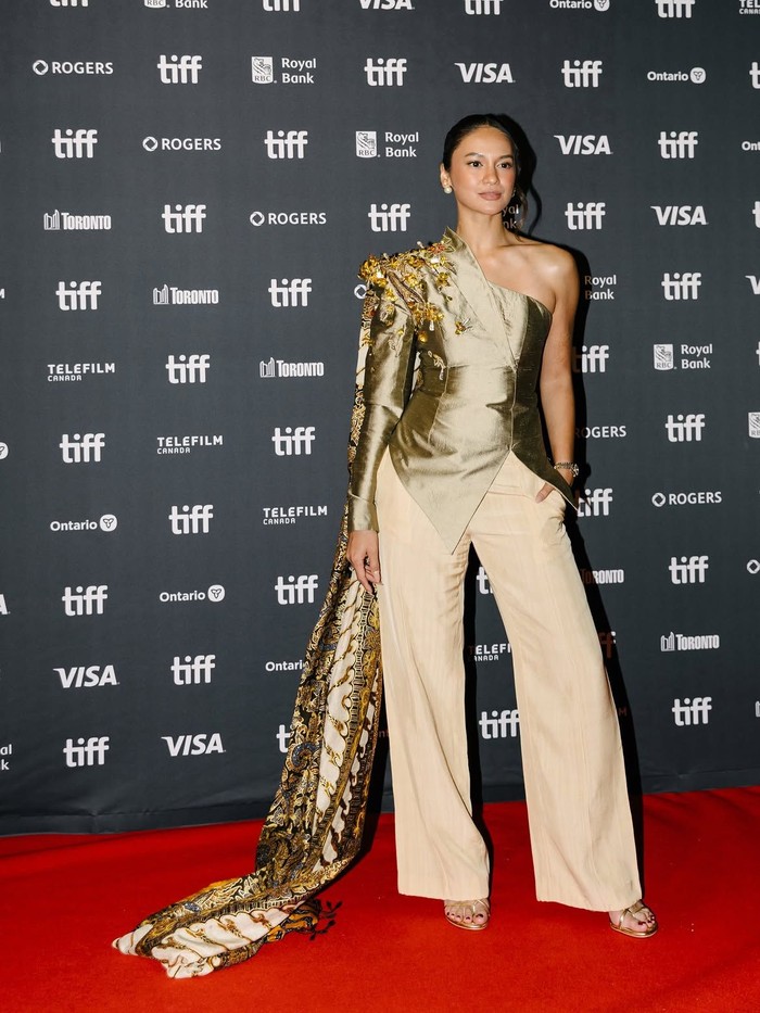 Hana Malasan tampil memukau dalam balutan busana gold couture saat menghadiri TIFF 2026. Detail drapery, aksen floral metalik, dan train panjang membuat penampilannya terlihat elegan sekaligus statement./ Foto: instagram.com/hanamalasan