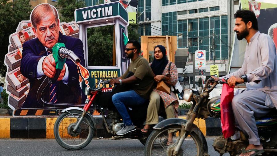 Pengendara sepeda motor melintas di dekat potret Perdana Menteri Pakistan Shehbaz Sharif—yang dipasang sebagai corak protes terhadap kenaikan nilai bahan bakar di tengah bentrok AS-Iran—menjelang peluncuran nasional program pemerintah nan menawarkan subsidi sebesar 100 Rupee per liter bagi sepeda motor, becak motor, dan kendaraan berkapasitas mesin hingga 800cc nan memenuhi syarat, di Karachi, Pakistan, 16 September 2026.