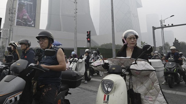 People ride on motorbikes and scooters on a polluted day in Beijing on September 17, 2026. (Photo by GREG BAKER / AFP)