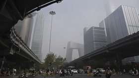People ride on a road on a polluted day in the central business district of Beijing on September 17, 2026. (Photo by GREG BAKER / AFP)