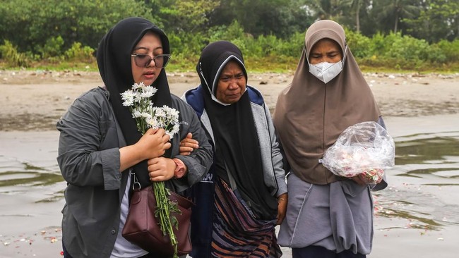 Sejumlah anggota keluarga dan kerabat dari salah satu jurnalis yang hilang kontak berfoto bersama usai tabur bunga di Pantai Pagedongan