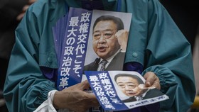 A man hands flyer with picture of Yoshihiko Noda, leader of the Constitutional Democratic Party (CDP), before his election campaign speech in front of Shibuya station in Tokyo on October 26, 2024. Candidates in Japan's super-tight parliamentary elect