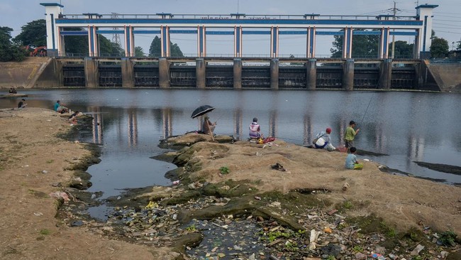 Warga memancing ikan di Sungai Cisadane yang airnya surut di Kota Tangerang, Banten, Jumat (18/9/2026). ]