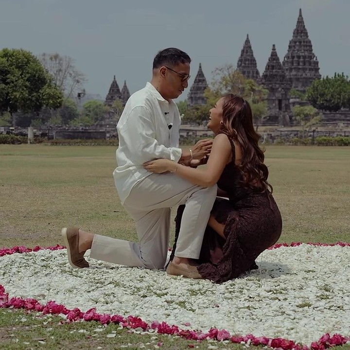 <p>Dennis tampaknya sudah merencanakan lamarannya dengan matang saat ia dan Marion Jola tengah liburan di Candi Prambanan. Keseriusan Dennis untuk meminang sang kekasih, dapat terlihat dari hiasan kelopak bunga mawar putih di atas rumput yang dibuat menyerupai lambang 'hati'. Di tempat ini, Dennis menguratakan niatnya. (Foto: Instagram @lalamarionmj/ @dennistalakua)</p>