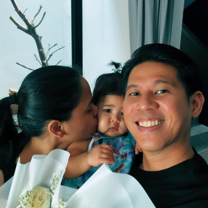 <p>Dalam postingan tersebut, Nino terlihat bersama Dhabitanissa yang sedang memegang bunga sambil mencium putri mereka. Nino pun menuliskan keterangan pada foto tersebut, &ldquo;Dua tahun pernikahan, tiga nama di kartu keluarga.&rdquo; (Foto: Instagram @ninokayam)</p>