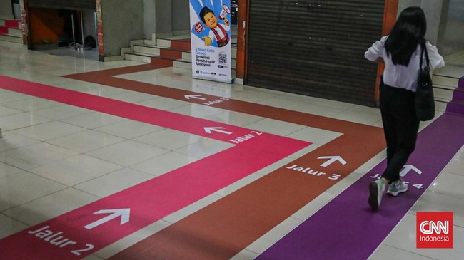 Sejumlah calon penumpang TransJakarta melintasi jalur pemandu di Halte Blok M, Melawai, Jakarta, Senin (21/9). (CNN Indonesia/Febria Adha L).
