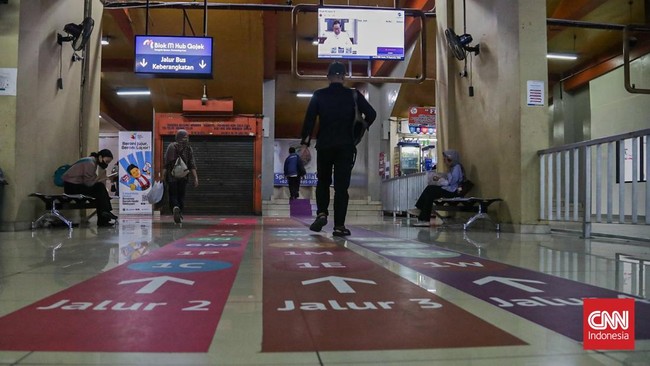 Sejumlah calon penumpang TransJakarta melintasi jalur pemandu di Halte Blok M, Melawai, Jakarta, Senin (21/9). (CNN Indonesia/Febria Adha L).