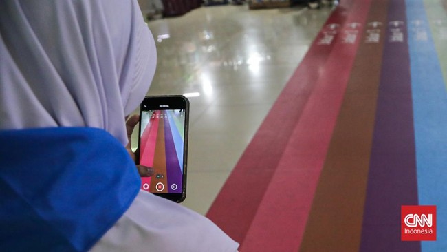 Sejumlah calon penumpang TransJakarta melintasi jalur pemandu di Halte Blok M, Melawai, Jakarta, Senin (21/9). (CNN Indonesia/Febria Adha L).