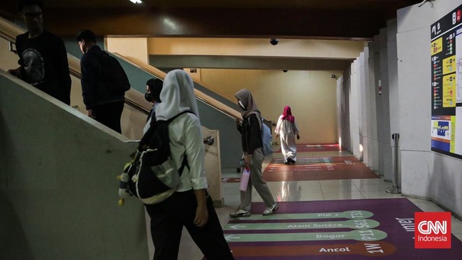 Sejumlah calon penumpang TransJakarta melintasi jalur pemandu di Halte Blok M, Melawai, Jakarta, Senin (21/9). (CNN Indonesia/Febria Adha L).
