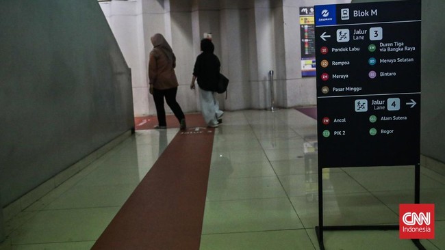 Sejumlah calon penumpang TransJakarta melintasi jalur pemandu di Halte Blok M, Melawai, Jakarta, Senin (21/9). (CNN Indonesia/Febria Adha L).