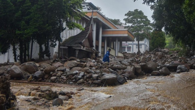 Warga berjalan melewati material banjir bandang di depan Kantor Bupati Solok, Arosuka, Kabupaten Solok, Sumatera Barat, Selasa (22/9/2026). Banjir bandang yang menerjang kawasan perkantoran di pusat kabupaten pada Senin (21/9) malam itu juga memutus