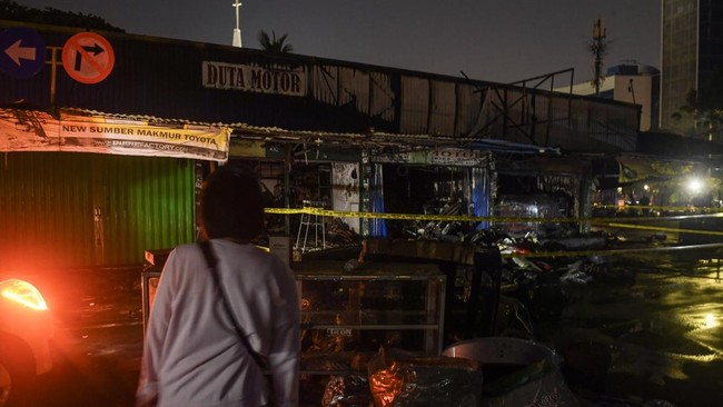 Pemilik bengkel dan toko onderdil mobil meilhat kiosnya yang terbakar di Pasar Mobil Kemayoran, Jakarta, Senin (21/9/2026). Kebakaran yang disebabkan akibat korsleting listrik tersebut menghanguskan tiga kios dan api berhasil dipadamkan setelah pemad