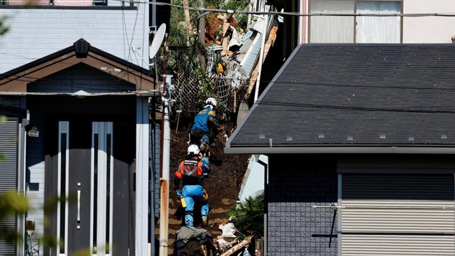 Rescue workers clear debris while searching for a missing person at a house hit by a landslide triggered by Typhoon Dujuan in Miura, Kanagawa Prefecture, Japan, September 22, 2026. REUTERS/Kim Kyung-Hoon