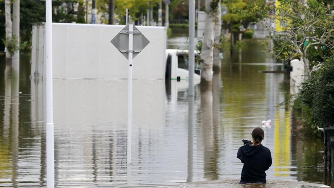 A woman walks at a residential area flooded due to heavy rain caused by Typhoon Dujuan in Sakura, Chiba Prefecture, Japan, September 22, 2026, in this photo taken by Kyodo. Mandatory credit Kyodo/via REUTERS ATTENTION EDITORS - THIS IMAGE HAS BEEN SU