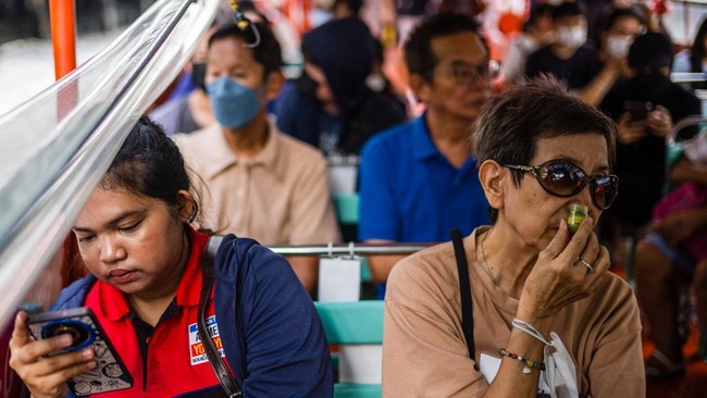 A woman (R) uses a nasal inhaler, or ya dom, as she and other commuters travel on the Khlong Saen Saep boat service that runs along the Saen Saep Canal in Bangkok on September 21, 2026. (Photo by ANTHONY WALLACE / AFP)