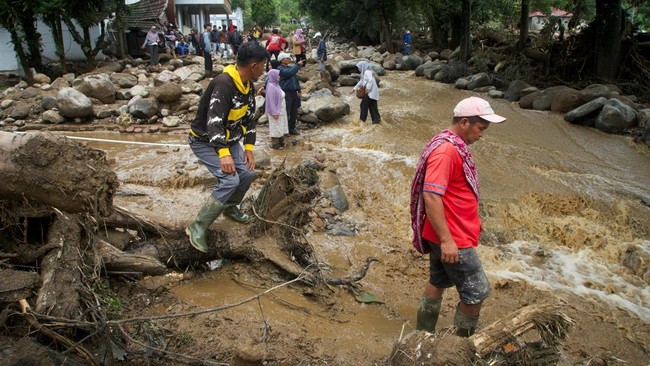 People walk in an area affected by flash floods following heavy rains in Solok, West Sumatra province, Indonesia, September 22, 2026.