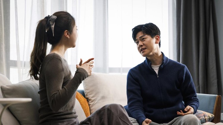 This is a young asian couple&period; They wear casual clothes&period; Sitting on the sofa in the living room at home&period; There was a quarrel between them&comma; and the man was very excited&period; Women are sad&period;