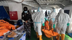 This handout photo taken and released on September 21, 2026 by Indonesia's Search and Rescue Agency (BASARNAS) shows search and rescue personnel in protective suits carrying a body bag containing a victim of the MV Virgo Transport 8 along the deck of