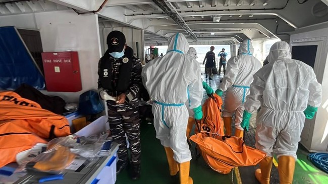 This handout photo taken and released on September 21, 2026 by Indonesia's Search and Rescue Agency (BASARNAS) shows search and rescue personnel in protective suits carrying a body bag containing a victim of the MV Virgo Transport 8 along the deck of