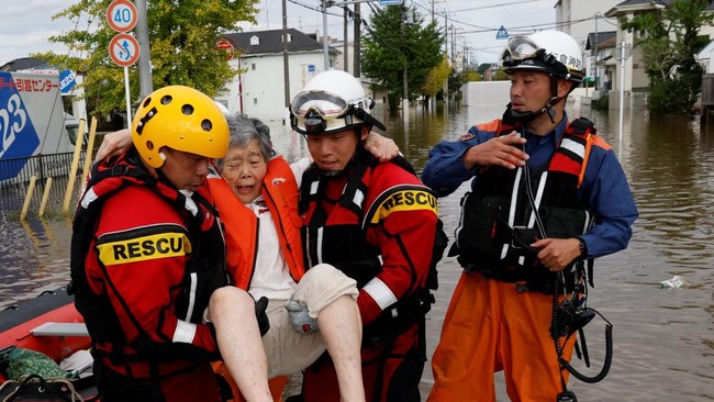 Firefighters carry an elderly woman after transporting her by boat from a flooded area, after Typhoon Dujuan brought torrential rain to Sakura, Chiba prefecture, Japan, September 22, 2026. REUTERS/Kim Kyung-Hoon