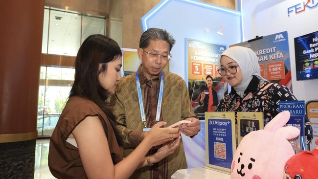 Direktur Utama Bank Mega, Kostaman Thayib (tengah) menyaksikan pengunjung yang tengah melakukan transaksi pembayaran menggunakan QRIS Cross Border - Korea Selatan dan QRIS Cross Border  Tiongkok (Cina) yang kini telah dapat dilakukan melalui aplikasi