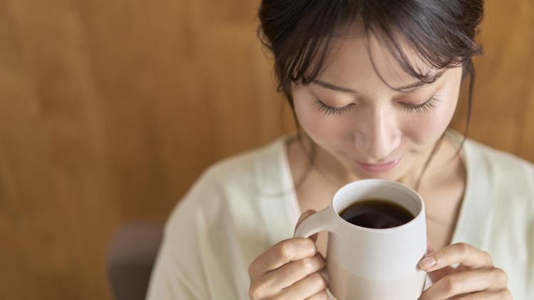 Young woman relaxing on sofa with hot drink