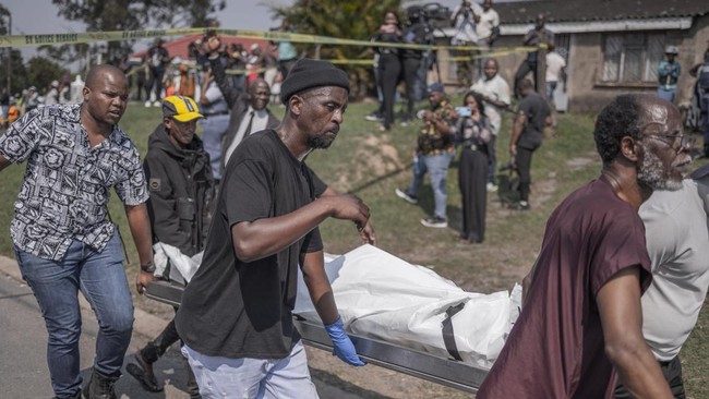 Community members carry the body of a victim following a mass shooting in the Ziko area of KwaMakhutha, south of Durban on September 23, 2026. Armed men stormed a home in the South African city of Durban and killed 11 people, the local government chi