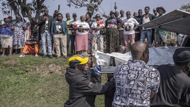 Community members assist to load the body of a victim into a mortuary van as others watch following a mass shooting in the Ziko area of KwaMakhutha, south of Durban on September 23, 2026. Armed men stormed a home in the South African city of Durban a