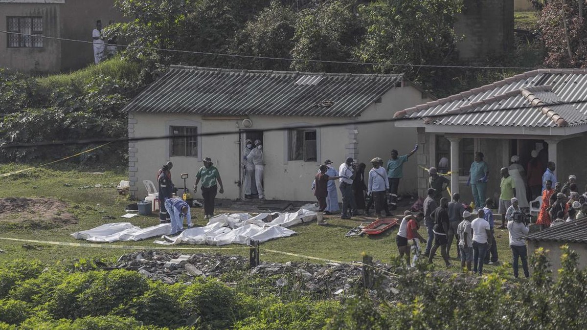 South African forensic investigators clear members of the community to conduct an investigation at the scene of a mass shooting in the Ziko area of KwaMakhutha, south of Durban on September 23, 2026. Armed men stormed a home in the South African city