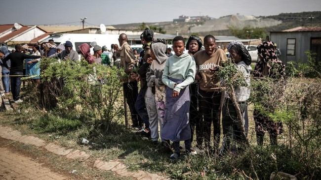 Residents gather near the scene where gunmen armed with assault rifles stormed a bar in Johannesburg on September 27, 2026. Gunmen killed at least 27 people in two mass shootings in South Africa's two main cities, police said on September 27, 2026, i