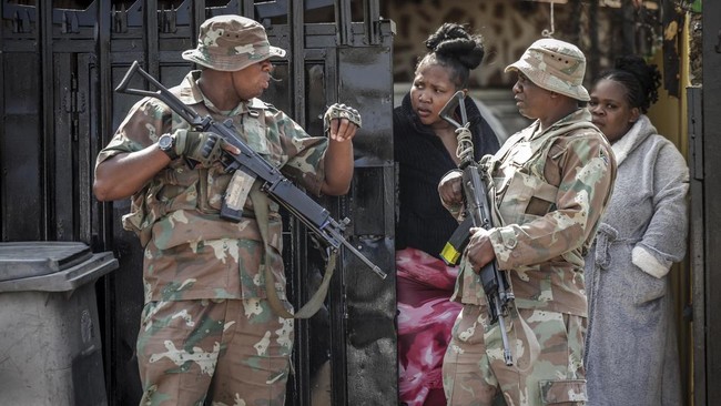 Members of the South African National Defence Force (SANDF) speak with residents near the scene where gunmen armed with assault rifles stormed a bar in Johannesburg on September 27, 2026. Gunmen killed at least 27 people in two mass shootings in Sout