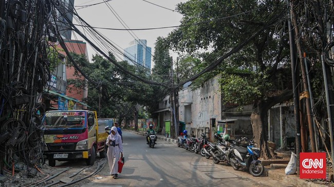 Sejumlah kabel optik tampak semrawut dan menjuntai di sepanjang area trotoar di kawasan Jalan Kuningan Barat, Jakarta, Senin, 28 September 2026. Kabel-kabel tersebut terlihat melintang di antara pepohonan sekitar jalan. CNN Indonesia/Febria Adha L