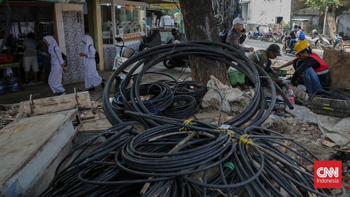Sejumlah kabel optik tampak semrawut dan menjuntai di sepanjang area trotoar di kawasan Jalan Kuningan Barat, Jakarta, Senin, 28 September 2026. Kabel-kabel tersebut terlihat melintang di antara pepohonan sekitar jalan. CNN Indonesia/Febria Adha L