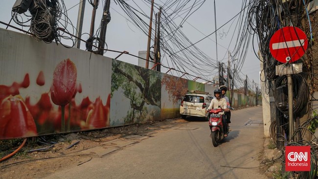 Sejumlah kabel optik tampak semrawut dan menjuntai di sepanjang area trotoar di kawasan Jalan Kuningan Barat, Jakarta, Senin, 28 September 2026. Kabel-kabel tersebut terlihat melintang di antara pepohonan sekitar jalan. CNN Indonesia/Febria Adha L