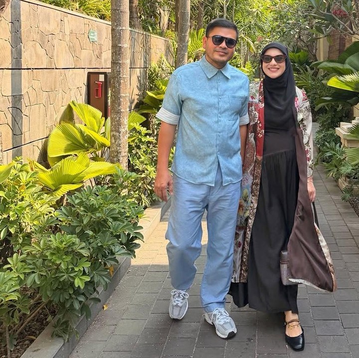 <p>Gaya kasual nan elegan terpancar dari Irish Bella yang memadukan gamis hitam dengan outerwear bermotif, disandingkan dengan Haldy yang mengenakan stelan biru santai. Keduanya tak lepas bergandengan tangan sepanjang berjalan.(Foto:Instagram @_irishbella_)</p>