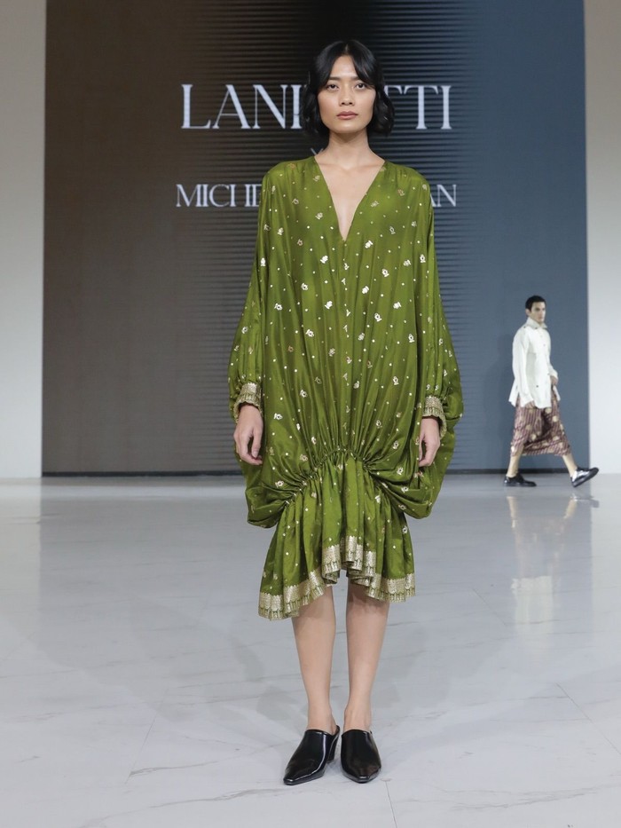 Salah satu koleksinya menampilkan dress longgar berwarna hijau dengan leher model V, serta potongan lengan balon. Menariknya, ada kerutan di bagian bawah yang menciptakan efek drapery balon yang unik. (Foto: Dok. Senayan City)