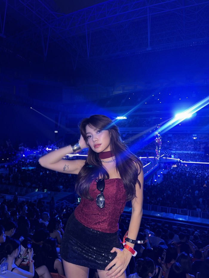 Regina Phoenix tampil feminin dan glamor saat menonton konser The Weeknd di Jakarta. Ia mengenakan bustier lace burgundy yang dipadukan dengan rok mini hitam bertekstur sequin, serta aksesori silver yang melengkapi penampilannya/Foto: Instagram/reginaaphx