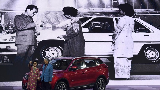 Malaysia's Prime Minister Mahathir Mohamad (R) and his wife Siti Hasmah Mohamad Ali pose with the 2019 Proton X70 SUV during an official launching ceremony in Kuala Lumpur on December 12, 2018. (Photo by Mohd RASFAN / AFP)