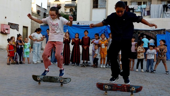 Palestinian girls skateboard as children look on, in Gaza City, September 23, 2026. REUTERS/Mahmoud Issa