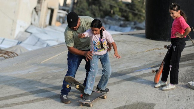Skateboarder, displaced coach and Gaza Skate Team leader Rajab Al-Rifi instructs Palestinian girls as they skate on the ruins of buildings destroyed during the war, in Gaza City, September 24, 2026. REUTERS/Dawoud Abu Alkas