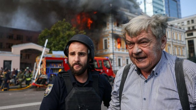 A man (R) who used a ladder to escape from a burning building walks, as smoke rises from an administrative building hit by a Russian jet-powered drone strike, amid Russia's attack on Ukraine, in Kyiv, Ukraine, September 28, 2026. REUTERS/Thomas Peter