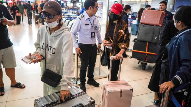 Passengers walk with baggage claimed from Thai Airways flights at Suvarnabhumi International Airport, after heavy rain and flooding disrupted the airline's ground operations, in Bangkok, Thailand, September 29, 2026. REUTERS/Athit Perawongmetha