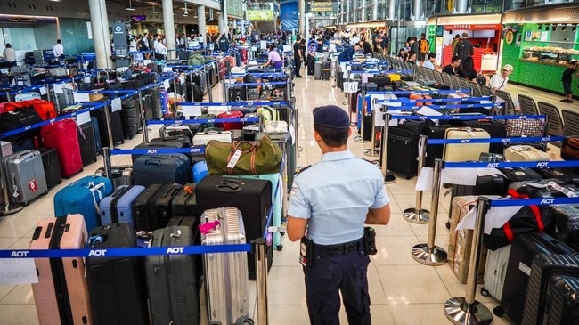 A member of airport security stands next to baggage from Thai Airways flights at Suvarnabhumi International Airport, after heavy rain and flooding disrupted the airline's ground operations, in Bangkok, Thailand, September 29, 2026. REUTERS/Athit Pera