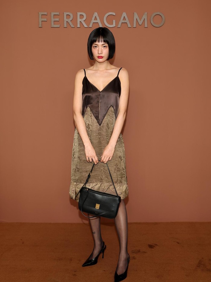 Nana mengenakan slip dress ringan yang menggabungkan dua material dan warna. Padu padan dengan tas dan heels hitam serta tanpa tambahan perhiasan membuat gaya&nbsp;terfokus pada dress/ Foto: Courtesy of Ferragamo Getty Images for Ferragamo /Daniele Venturelli