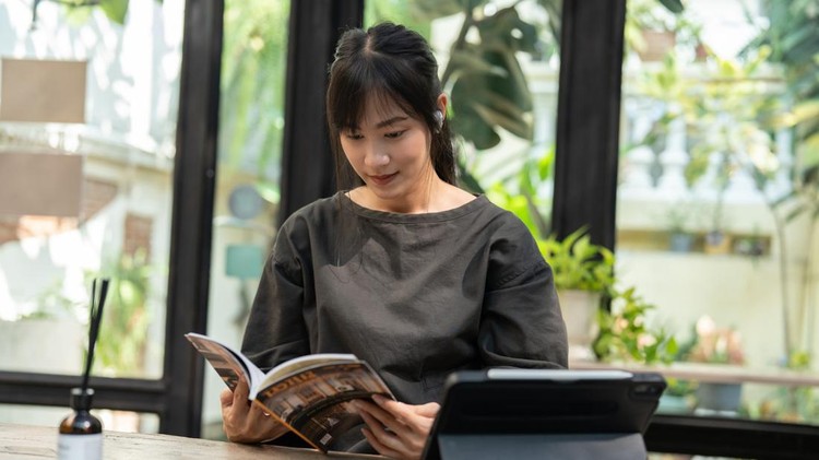 Calm Morning Routine&colon; Asian Woman Finds Serenity in Reading Book at Cafeteria During Early Hours&period;