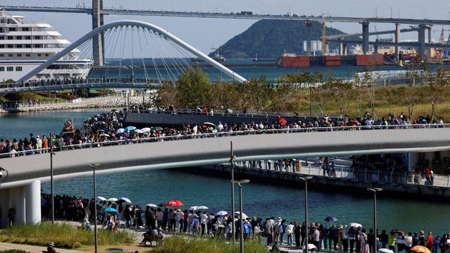 People gather on a bridge and along a canal where a shark nicknamed