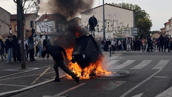 A protester throws a garbage bin into a fire outside the Lycee Deodat-de-Severac high school as part of nationwide protests by high school students to demand the hiring of substitute teachers, increased resources and better learning conditions, in To