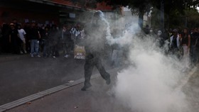 A protester throws a canister tear gas amid clashes during a gathering outside the Lycee Deodat-de-Severac high school as part of nationwide protests by high school students to demand the hiring of substitute teachers, increased resources and better