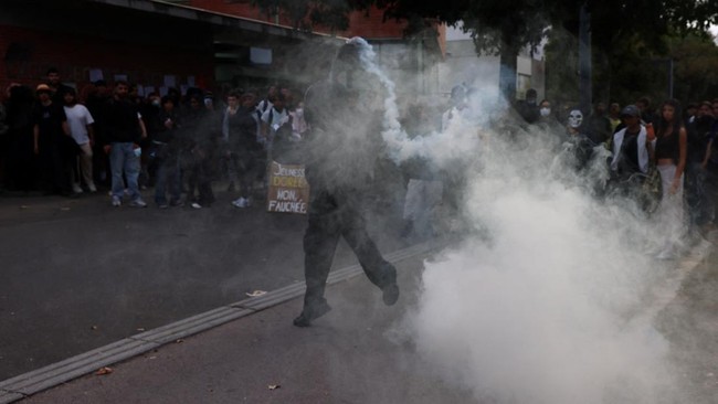 A protester throws a canister tear gas amid clashes during a gathering outside the Lycee Deodat-de-Severac high school as part of nationwide protests by high school students to demand the hiring of substitute teachers, increased resources and better